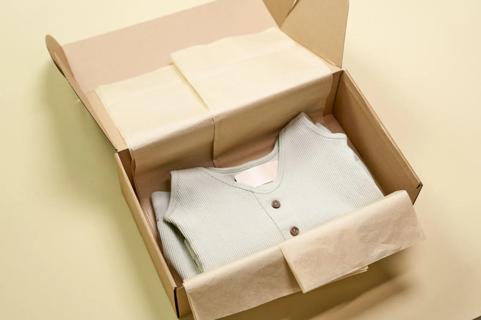A folded shirt packed in a kraft box with tissue paper