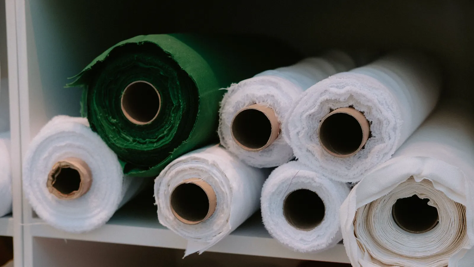 Rolls of cream and white cloth on a shelf