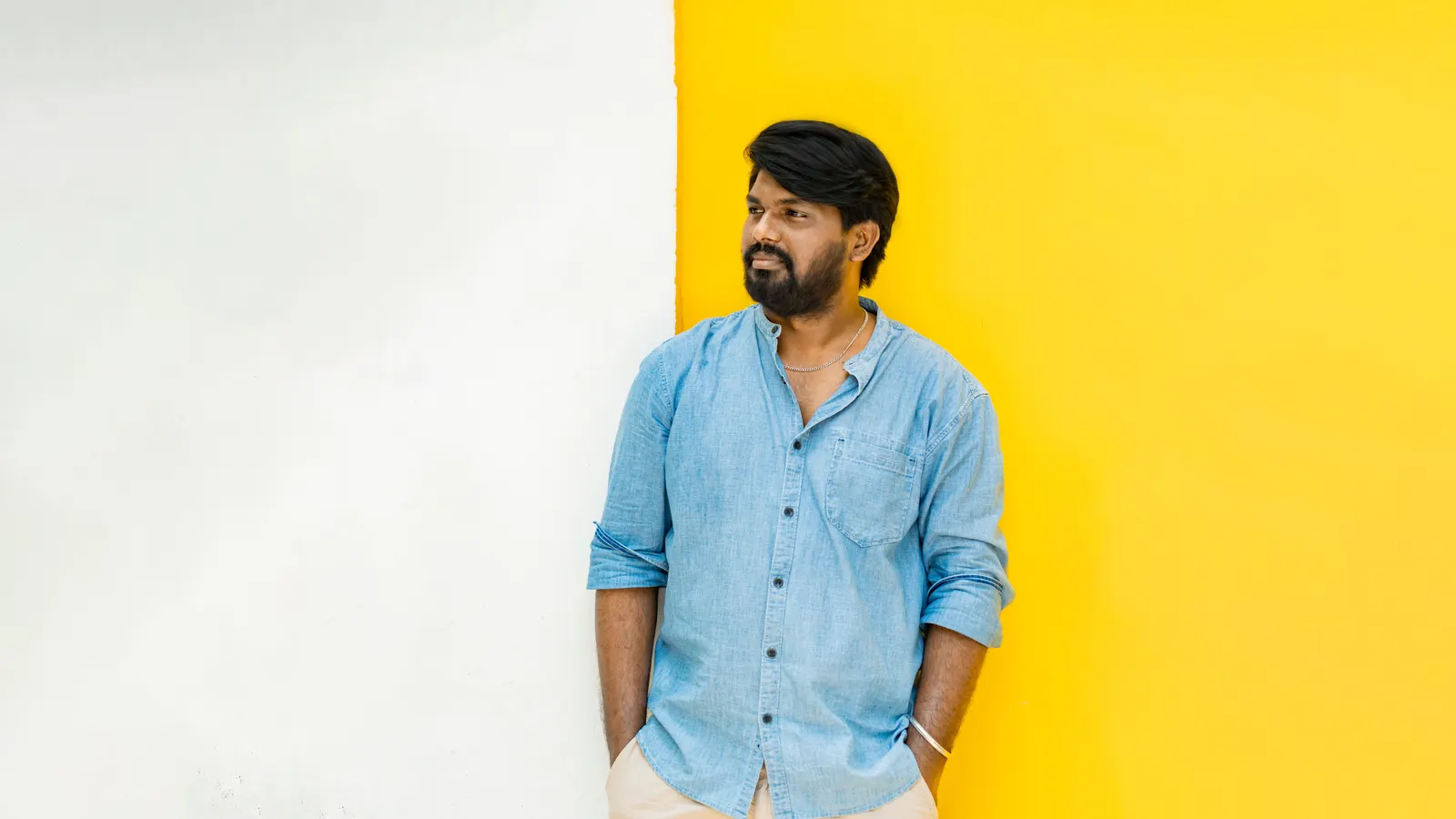 A man in a light blue shirt against a white and yellow wall