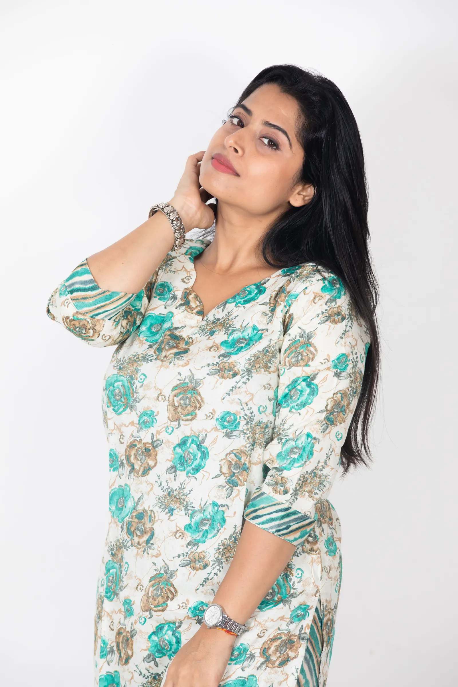 A woman in a blue and cream floral kurta against a plain white backdrop